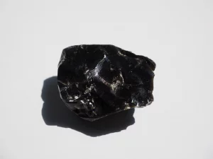 Black Obsidian raw crystal on natural surface.